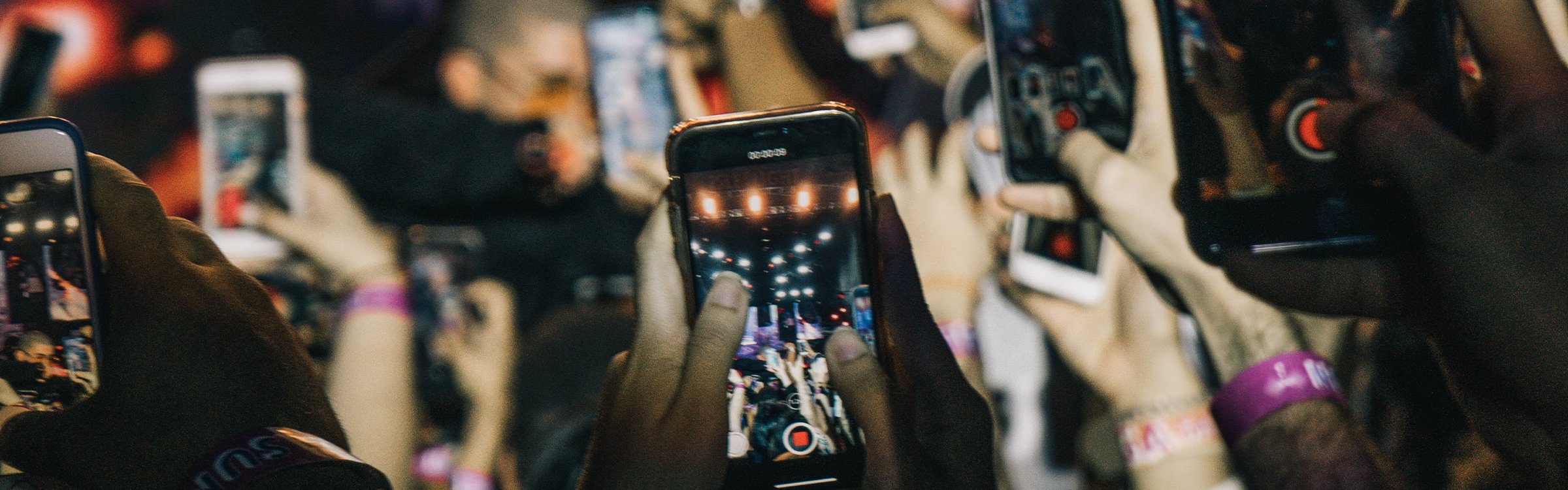 hands holding cell phones at an event